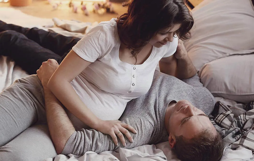 Nosečnica in partner sproščeno ležita na postelji